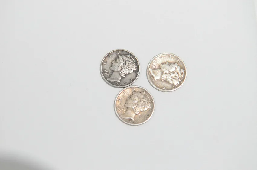 Three Mercury dimes lined up on a white surface